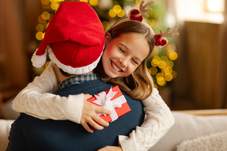 Happy teen girl hugging father, greeting with New Year holiday receiving present, exchanging gifts on Christmas morningの写真素材