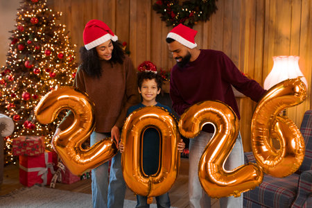 Happy African American family of three celebrating upcoming New Year, holding large balloons, posing...