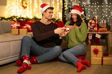 Man making surprise for his girlfriend, romantic couple celebrating New Year and Christmas together at homeの写真素材