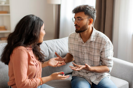 Spouses having conflict, experiencing crisis in relationships, sitting on sofa and shouting at each otherの写真素材