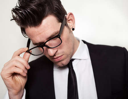 Confident young man holding black glasses.