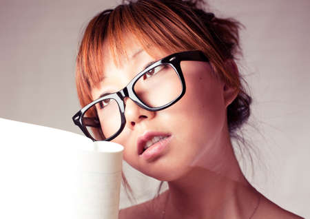 Asian girl holding a textbook. Wear a big black glasses.の写真素材