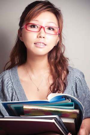Asian girl holding a textbook. Wear glasses.の写真素材