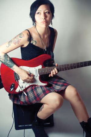 Funky young woman with her red hot guitar.の写真素材
