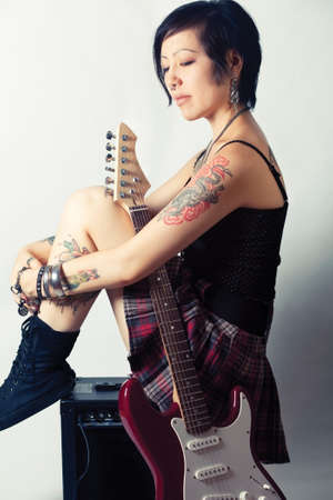 Funky young woman with her red hot guitar.の写真素材