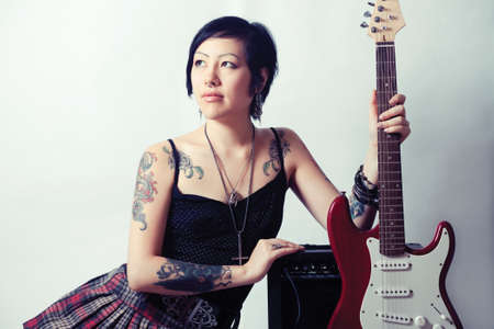 Funky young woman with her red hot guitar.の写真素材
