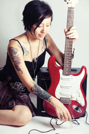 Funky young woman with her red hot guitar.の写真素材