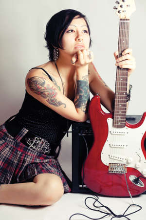 Funky young woman with her red hot guitar.の写真素材