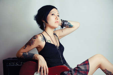 Funky young woman with her red hot guitar.の写真素材