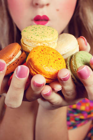 A young woman loves her sweet macaron.の写真素材