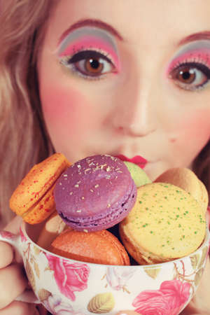 A young woman loves her sweet macaron.の写真素材