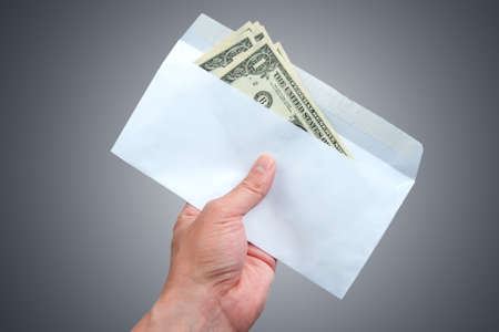 Hand and envelope with cash in dollars isolated on white backgroundの写真素材