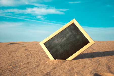closeup of a chalkboard with a wooden frame, placed on the sand of a beach