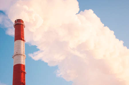 Smoking chimneys against the blue sky / air pollution / steam coming out of the pipeの写真素材