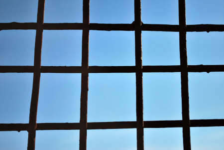 Grid of steel bars with blue sky background.の写真素材