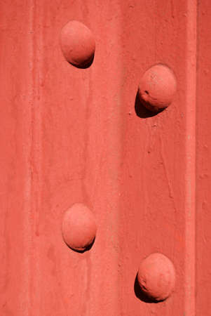 A closeup, detailed view of two steel girders, bolted together and painted red.の写真素材