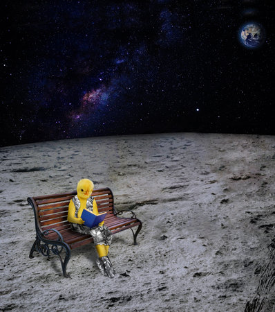 Chick dressed as human is reading a book. The chick sitting on the bench is reading a book. The living creature on the moon reads a book.の写真素材