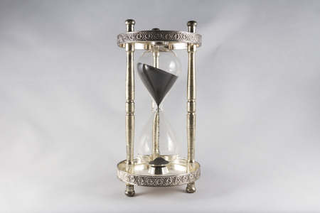 Antique hourglass, black sand, textured background. Centre image, landscape, top half mostly full.の写真素材