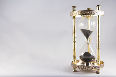 Antique hourglass, black sand, textured background. Right of image, blank space on left, landscape, top half partly full.の写真素材