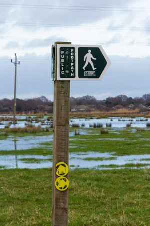 Dorset County Council footpath sign, flooded Christchurch meadows in background. Dorset, England, United Kingdom.のeditorial素材
