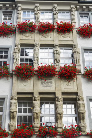 Three floors of windows, each has a window box with red geraniums. Munich, Bavaria, Germany, Europe.の写真素材