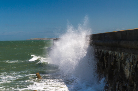 In high wind, waves crash against the Victorian Breakwater (1.7 miles long) at Holyhead, Anglesey, Wales, United Kingdom.の写真素材