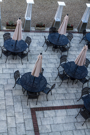 Looking down on four outside restaurant circular tables with umbrellas.の写真素材