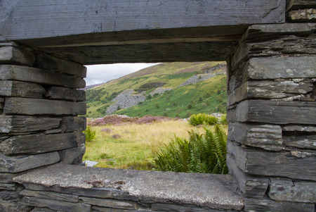 View of Welsh hillside with slate quarry through derelict window frame.の写真素材