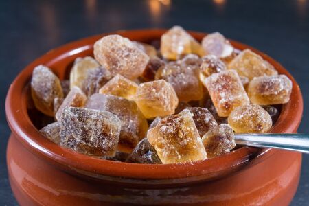Macro of German Rock Sugar, brauner Kandis in a terracotta brown bowl and metal spoon. Close up.の写真素材