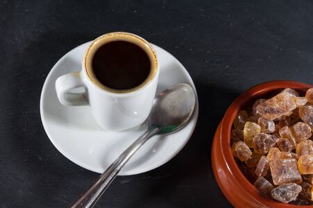 German Rock Sugar, brauner Kandis in a terracotta brown bowl with cup of expresso coffee.の写真素材