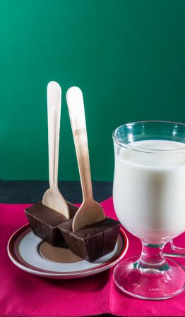 Belgian hot chocolate stirrers with milk in glass mug, purple napkin green background.の写真素材