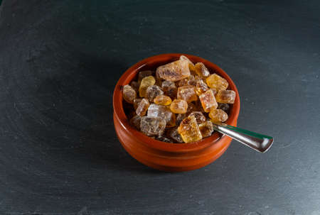Macro of German Rock Sugar, brauner Kandis in a terracotta brown bowl and metal spoon. Close up.の写真素材