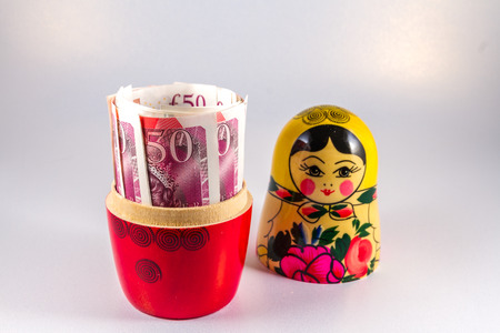 Roll of 50 pound sterling notes hidden in matryoshka Russian doll.の写真素材