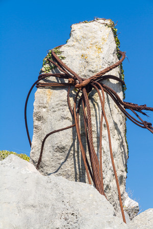 Old rusty iron cables looped around a limestone rock in a quarry.の写真素材