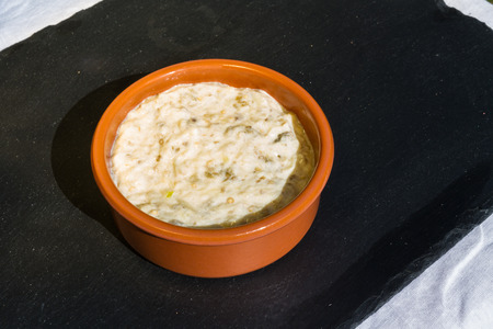 Home made aubergine dip in orange ceramic bowl and on slate mat, outside on linen covered table.の写真素材