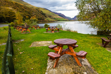Evening view of picnic tables on grass by lake.の写真素材