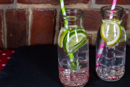 Childrens healthy water with ice, lemon, lime, pomegranate seeds and straws.の写真素材