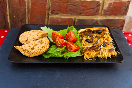 Platter of Pissaladiere French onion tart with rustic bread and tomato lettuce salad.の写真素材
