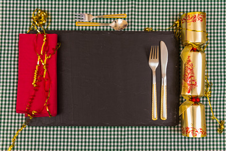 Place laid for Xmas dinner, knife, fork, Christmas cracker, napkin on slate mat.の写真素材