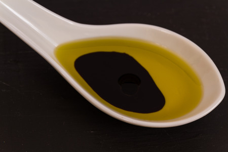 Olive oil and balsamic vinegar presented in a ceramic spoon with a slate background, macro.の写真素材