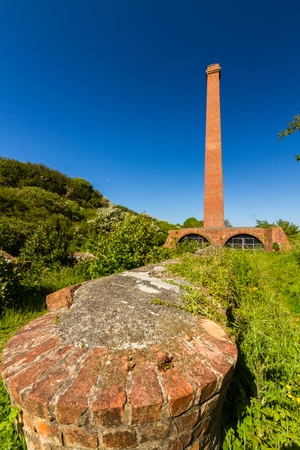 Old brick ruins with tall chimney and  blue sky. Cemaes Brickworks, Anglesey, Wales, United Kingdom, Europeの写真素材