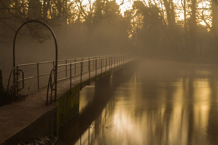 Foot bridge over river Frome during twilight with evening mist. Moreton, Dorset, England, United Kingdomの写真素材