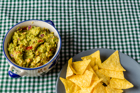Bowl of homemade guacamole, ready for eating with tortilla chips on the side.の写真素材