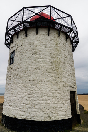 Small white squat white lighthouse with red top. Burry Port, Llanelli, Carmarthenshire, Wales.の写真素材
