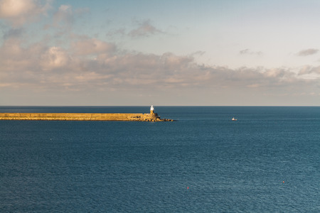 Fishguard harbour breakwater with lighthouse, evening light. Pembrokeshire, Wales, United Kingdom.の写真素材