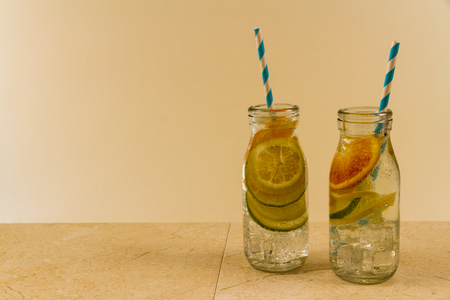 Childrenâs sparkling water drinks in bottles with straw. Slices of orange, lemon and lime. Copy space on left.の写真素材