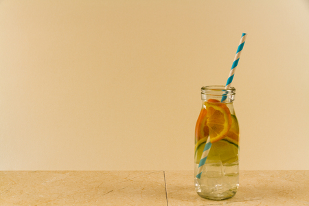 Childrenâs water drink in bottle with straw. Slices of orange, lemon and lime. Copy space on leftの写真素材