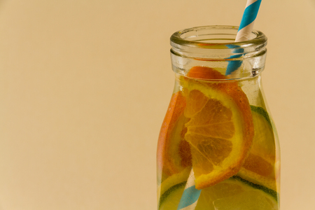 Childrenâs water drink in bottle with straw. Slices of orange, lemon and lime. Copy space on leftの写真素材