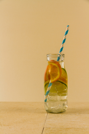 Childrenâs water drink in bottle with straw. Slices of orange, lemon and lime. Copy space on leftの写真素材