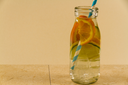 Childrenâs water drink in bottle with straw. Slices of orange, lemon and lime. Copy space on leftの写真素材